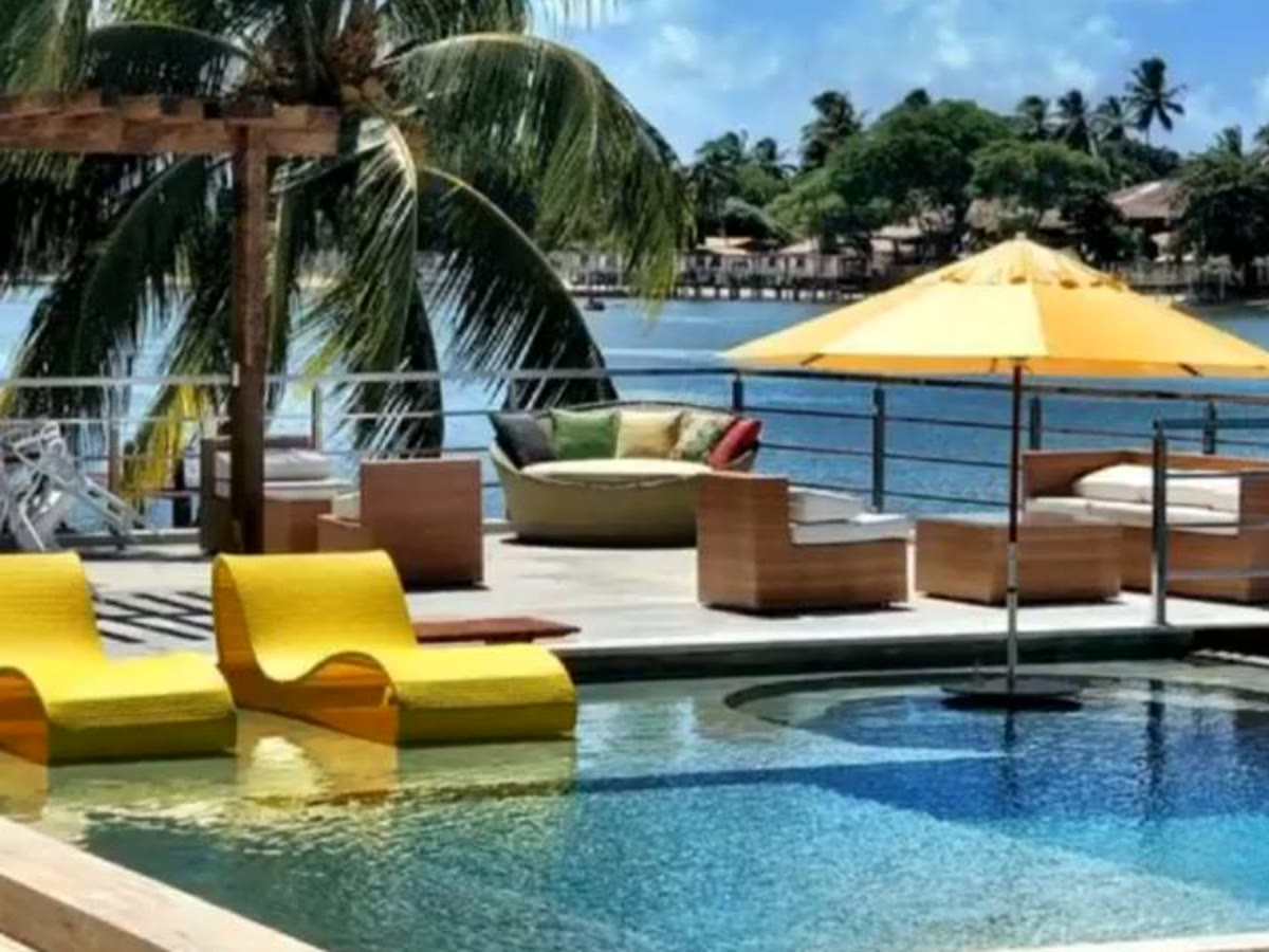 Piscina com espreguiçadeiras amarelas e deck com vista para a água