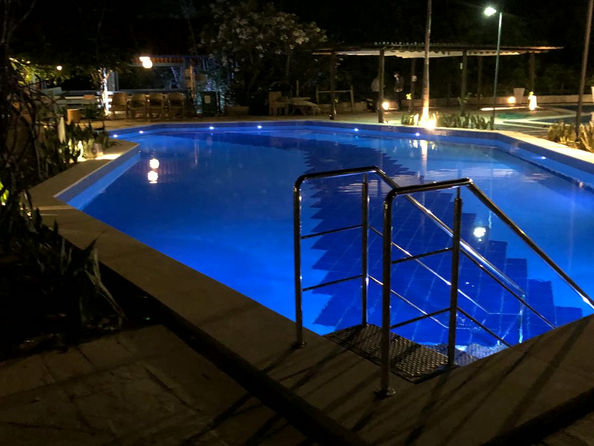 Piscina iluminada à noite com escada de acesso